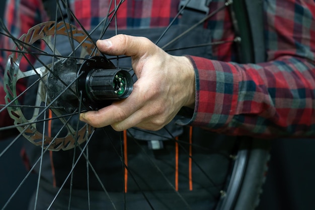 Riparazione di mountain bike Meccanico di biciclette in officina Sostituzione del grasso e dei cuscinetti del mozzo della bicicletta Il meccanico tiene una ruota in mano Primo piano del cuscinetto