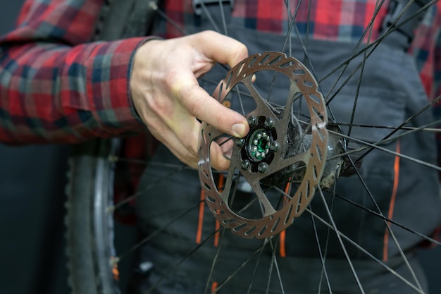 Riparazione di mountain bike Meccanico di biciclette in officina Sostituzione del grasso e dei cuscinetti del mozzo della bicicletta Il meccanico tiene una ruota in mano Primo piano del cuscinetto