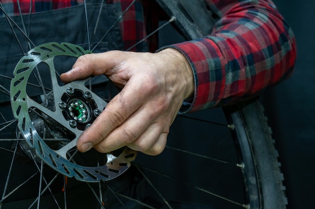 Riparazione di mountain bike Meccanico di biciclette in officina Sostituzione del grasso e dei cuscinetti del mozzo della bicicletta Il meccanico tiene una ruota in mano Primo piano del cuscinetto