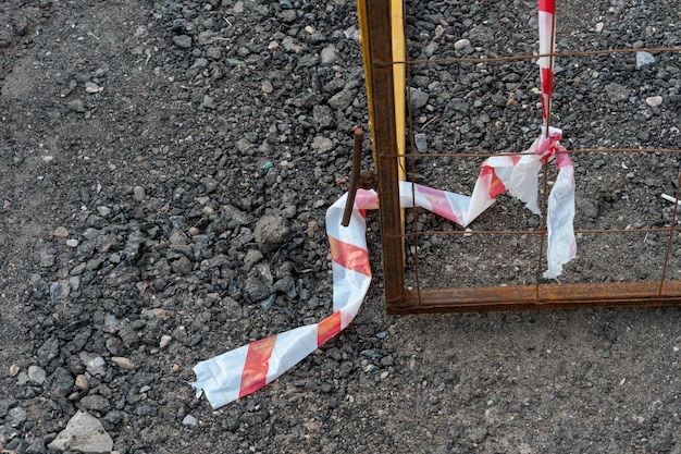 Riparazione di strade Posa di nuovo asfalto Barriera protettiva davanti alla fossa sulla strada Un nastro bianco e rosso segnala il pericolo