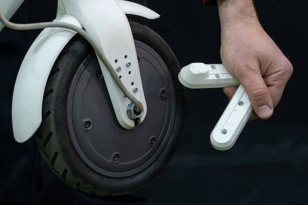 Riparazione di un moderno scooter elettrico in un'officina professionale Nelle mani del meccanico lo strumento e le parti smontate dello scooter sono nelle mani Primo piano di ruote e pneumatici