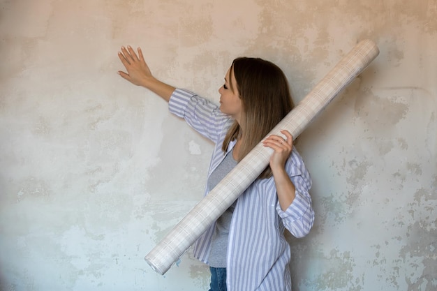 Riparazione e miglioramento della casa. una bella ragazza tiene la carta da parati tra le mani