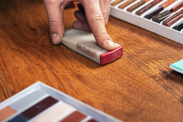 Riparazione e restauro di laminati e parquet. sigillando graffi e scheggiature. il maestro cancella una superficie di legno funzionante.