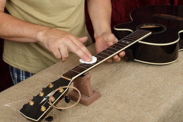 Riparazione e servizio di chitarra Inumidimento e impregnazione del lavoratore di un olio per chitarra nero al manico della tastiera