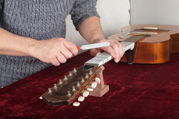 Riparazione e servizio di chitarra Operaio per affilare i tasti del manico della chitarra con strumenti speciali