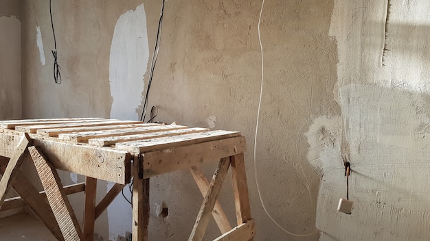 Riparazione nell'appartamento. Scala in legno grunge. Il concetto di registrazione dell'appartamento. panca per dipingere il soffitto.