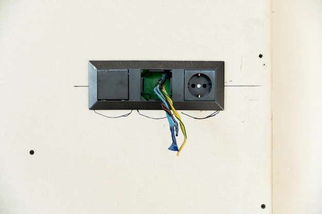 Riparazione presa su sfondo bianco fili elettrici che sporgono dalla presa