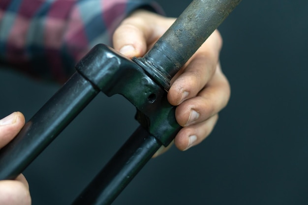 Riparazione professionale della bicicletta in officina Il meccanico ripara la vecchia forcella rigida della bicicletta Sostituzione del cuscinetto del piantone dello sterzo Dettagli di una forcella della bicicletta su sfondo nero