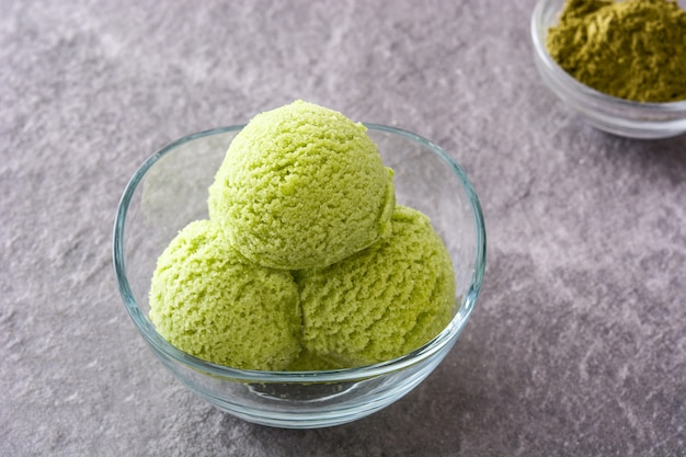 Ripartitori di matcha del tè verde in ciotola a cristallo su pietra grigia