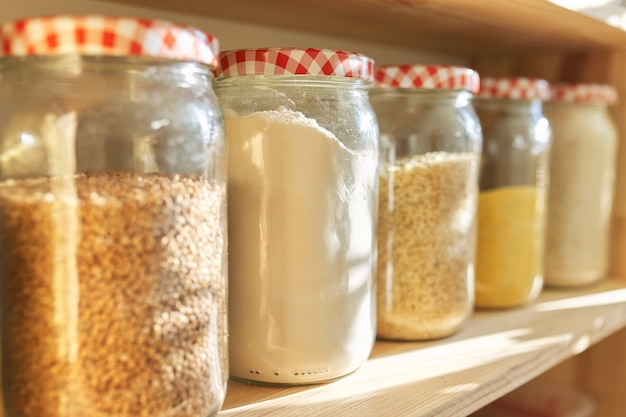 Ripiani in legno in dispensa per la conservazione degli alimenti, prodotti a base di cereali in barattoli di stoccaggio.