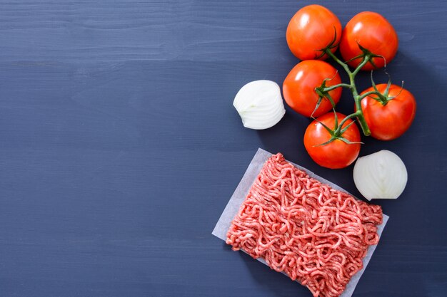 Ripieno con pomodori rossi su un ramo e cipolle affettate su un fondo di legno grigio con spazio di copia