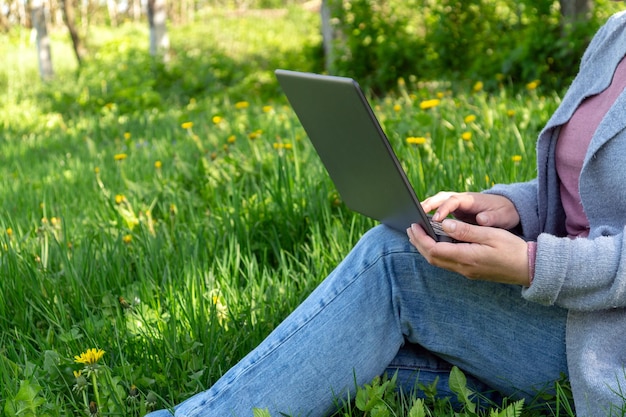 Riposa con un laptop nella natura nel parco in una giornata di sole sullo sfondo dell'erba verde