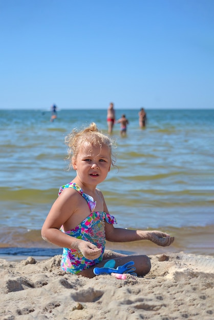 Riposa in riva al mare. La bambina gioca con la sabbia sulla spiaggia. Ragazza che gioca con i giocattoli in riva al mare.