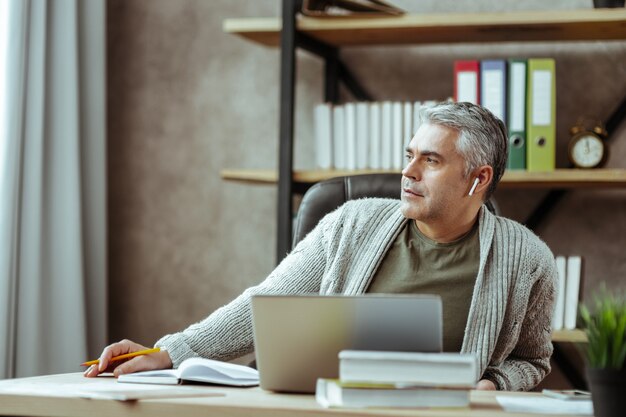 Riposo dal lavoro. Un bell'uomo premuroso che guarda nella finestra mentre si riposa dal lavoro