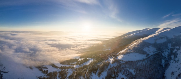 Ripresa aerea della maestosa alba nelle montagne La valle tra le montagne è ricoperta di nebbia ed è illuminata dai caldi raggi del sole nascente Montagne coperte di foresta naturale