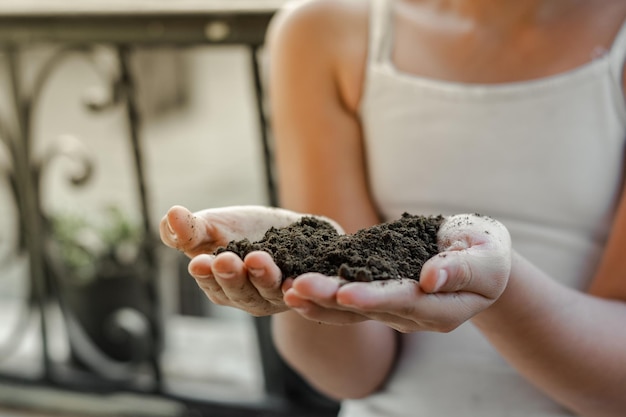 Ripresa dettagliata delle mani di una bambina che tiene un po' di terriccio per piantare in giardino