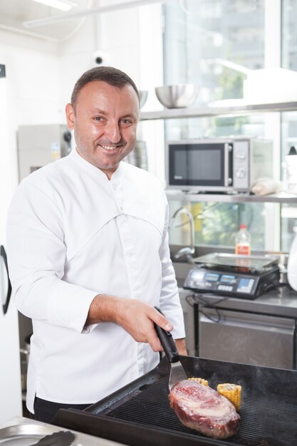 Ripresa verticale di un felice chef del ristorante che sorride mentre lavora in cucina