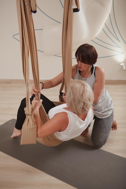 Ripresa verticale di una donna anziana che si esercita allo studio di yoga al volo con personal trainer