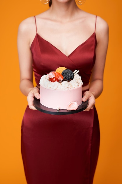 Ripresa verticale di una donna elegante con un vestito rosso che porta una torta di compleanno