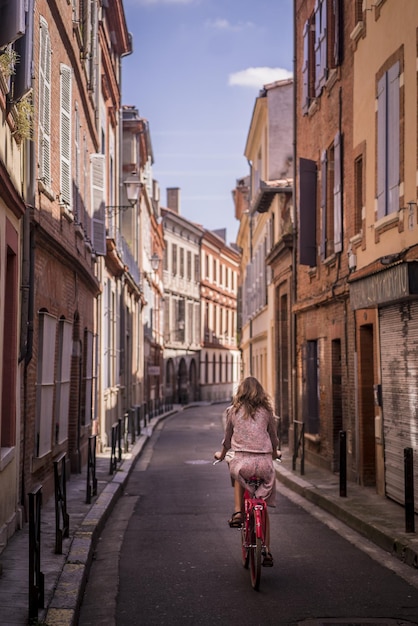 Ripresa verticale di una donna in sella a una bicicletta per le strade di Tolosa, in Francia
