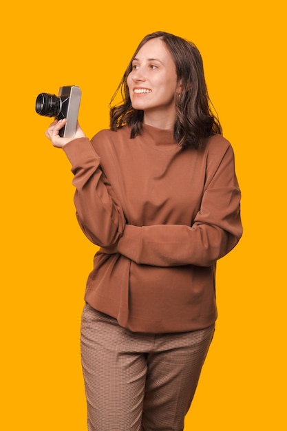Ripresa verticale di una giovane donna che tiene una macchina fotografica vintage e guarda da parte