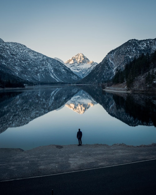 Ripresa verticale di una persona in piedi vicino al lago Riffelsee nelle montagne del Cervino in Svizzera