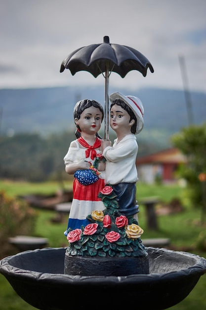 Ripresa verticale di una statua di una giovane coppia che tiene un ombrello all'aperto