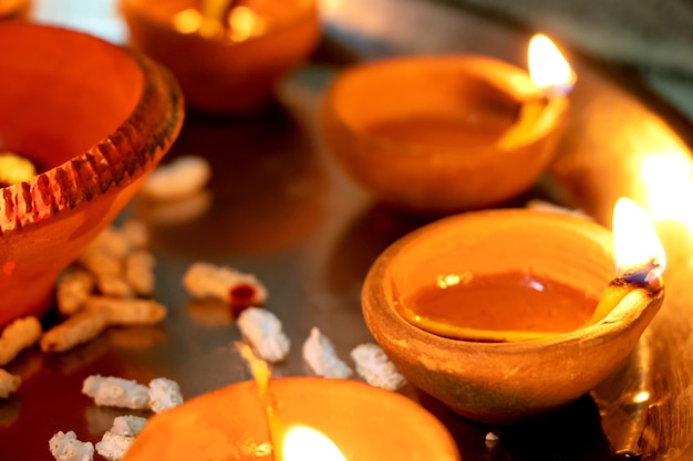 Riprese macro di diyas che vengono accese a mano o con una candela per la festa religiosa indù di Diwali. Questi colorati vasi di terracotta contengono olio e uno stoppino di cotone per illuminare