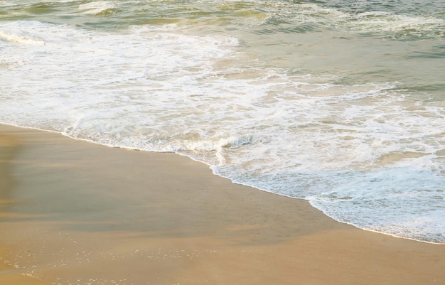 Risacca sulla spiaggia sabbiosa alla luce del sole