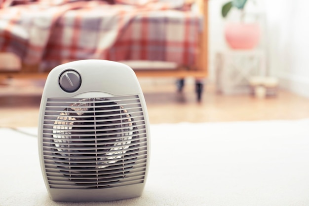 Riscaldatore elettrico sul pavimento del soggiorno con divano sullo sfondo