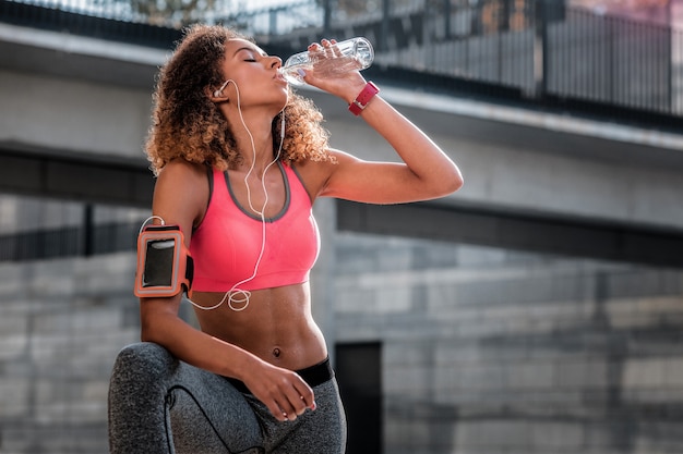 Rischio di disidratazione. Piacevole bella donna che beve acqua pur essendo molto assetata