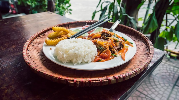 Riso al curry giapponese con verdure, frutti di mare, carne, carote e patate su tavola di legno Cucina asiatica in un ristorante all'aperto