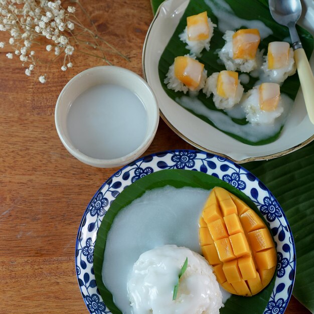 Riso appiccicoso con mango maturo nel latte di cocco Autentici dessert tailandesi su un tavolo di legno