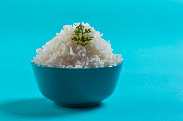 Riso basmati bianco normale cotto con corriander in una ciotola blu su blu