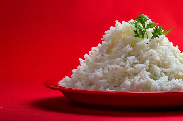 Riso basmati bianco normale cotto in un piatto rosso sul rosso