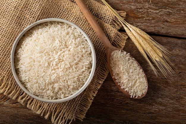 Riso bianco crudo in una ciotola di ceramica su fondo di legno marrone