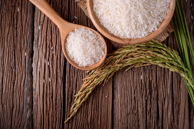 riso bianco in ciotola di legno e riso non macinato su fondo di legno
