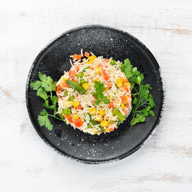 Riso bollito e verdure Risotto In un piatto nero Vista dall'alto Spazio libero per la copia