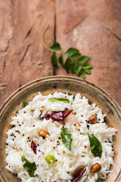 Riso cagliato o Dahi Bhat O Chawal con foglia di curry, arachidi e peperoncino- Servito in una ciotola su sfondo lunatico. Messa a fuoco selettiva