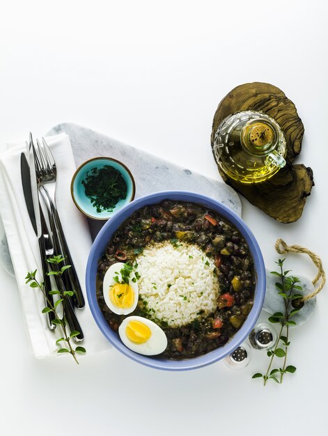 Riso con fagioli neri e uovo sodo sul tavolo con spezie e olio d'oliva