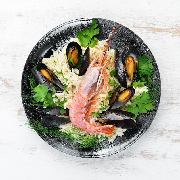 Riso con frutti di mare Risotto con gamberi e cozze In un piatto nero Vista dall'alto Spazio libero per la copia