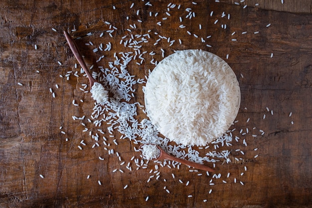 Riso crudo bianco in una ciotola su una tavola di legno