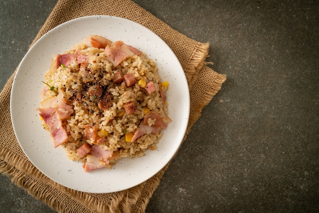 riso fritto con pancetta e peperoni neri su piatto bianco