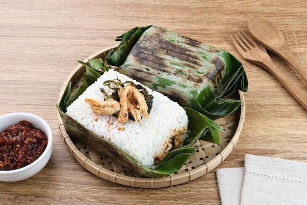 Riso Nasi Bakar con spezie avvolto in foglie di banana con pollo tritato piccante e foglie di basilico