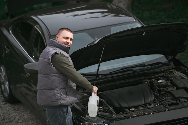 Risoluzione dei problemi dell'auto Uomo che diagnostica i problemi del motore sul portico Il proprietario dell'auto si trova davanti al cofano di un'auto