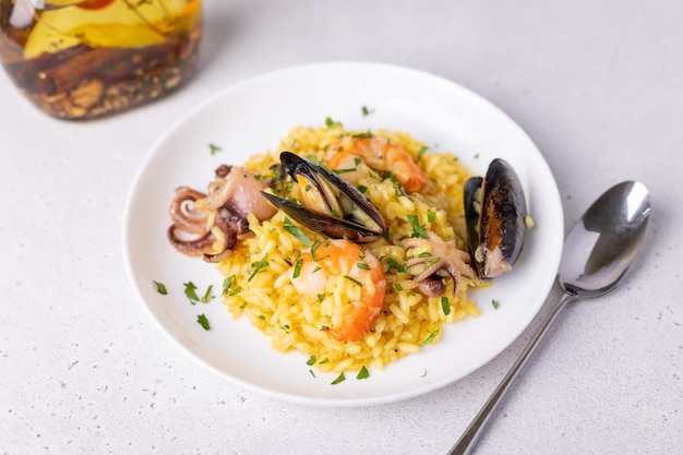 Risotto ai frutti di mare con zafferano e prezzemolo Riso Arborio con gamberi tigrati cozze e polipetti Piatto tradizionale italiano Primo piano fuoco selettivo