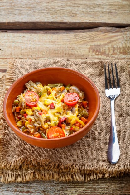 Risotto ai funghi in piatto di argilla su fondo di legno su tavola intagliata