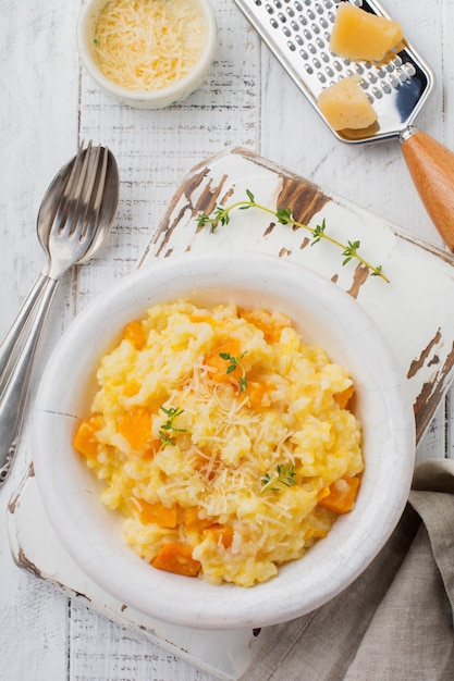 Risotto alla zucca con timo, aglio, parmigiano e vino bianco su fondo in legno chiaro Stile rustico