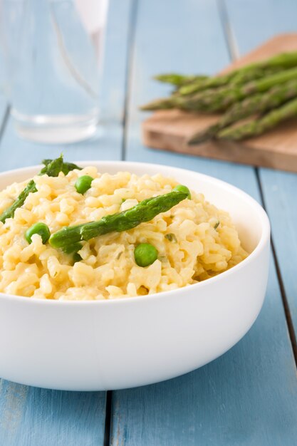 Risotto con asparagi prezzemolo e piselli sul tavolo di legno blu