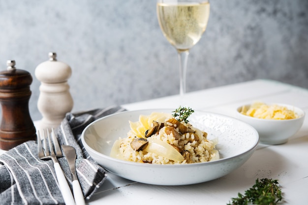 Risotto con funghi porcini e parmigiano su sfondo chiaro, fuoco selettivo